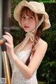 A woman in a white dress and a straw hat.