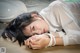 A woman laying on the ground with her head resting on her hands.