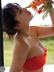 A woman in a red bikini holding a bunch of flowers.