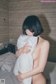 A naked woman holding a pillow on a bed.