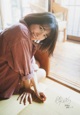 A woman sitting on the floor in front of a window.