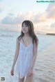 A woman in a white dress standing in the ocean.