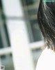 A woman with long black hair standing in front of a window.