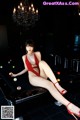 A woman in a red bodysuit sitting on a pool table.