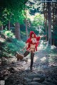 A woman dressed as a red riding hood in the woods.