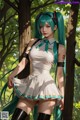 A woman with long green hair standing in the woods.