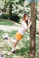 A woman leaning against a tree in a park.