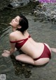 A woman in a red bikini sitting in the water.