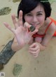 A woman in a red bathing suit holding a rock in her hand.