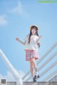 A young woman in a school uniform is standing on some stairs.