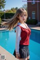 A woman in a school uniform standing next to a swimming pool.