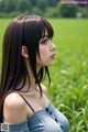 A woman with long black hair standing in a field.