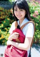 A young woman with a red backpack smiles at the camera.