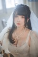 A woman in a wedding dress sitting on a chair.