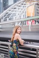 A woman in a colorful dress standing on a bridge.