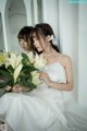 A woman in a white dress holding a bunch of white flowers.