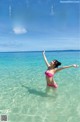 A woman in a pink bikini standing in the ocean.