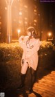 A woman standing on a boardwalk in the middle of a city at night.