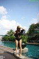 A woman in a black bathing suit standing by a pool.