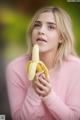 A woman holding a banana in front of her face.