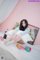 A woman sitting on top of a bed next to a bottle of soda.