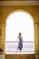 A woman in a blue dress standing on a balcony.