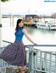 A woman in a blue top and a floral skirt posing for a magazine.